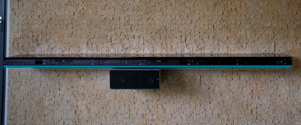 Steinwand mit Sideboard und beleuchteter Braun HiFi Stereoanlage